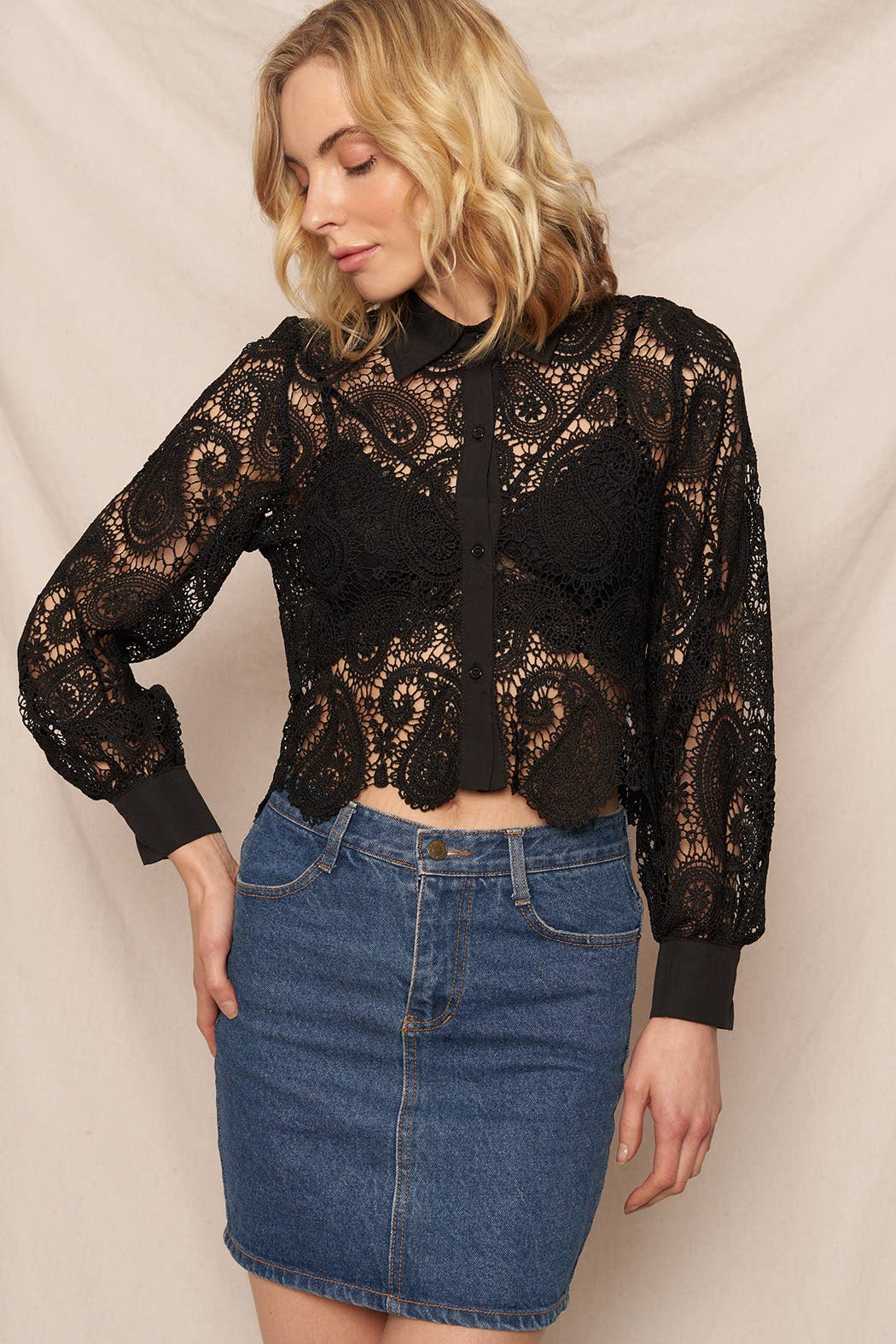 Woman in black lace top and denim skirt.