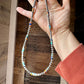 Turquoise & silver beaded necklace held in hand.