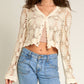 Woman wearing cream crocheted cardigan and jeans.
