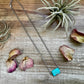 Turquoise stone necklace (BC239849) on rustic wood with flowers.