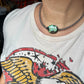Turquoise necklace on a person wearing a graphic tee.