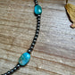 Turquoise and hematite bead necklace on wood