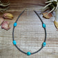 Turquoise beaded necklace on wood surface