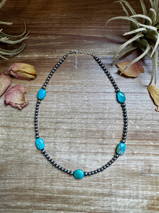 Turquoise beaded necklace on wood surface