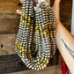 Hand holding beaded necklace with yellow accents