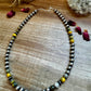 Silver and gemstone bead necklace on wood surface