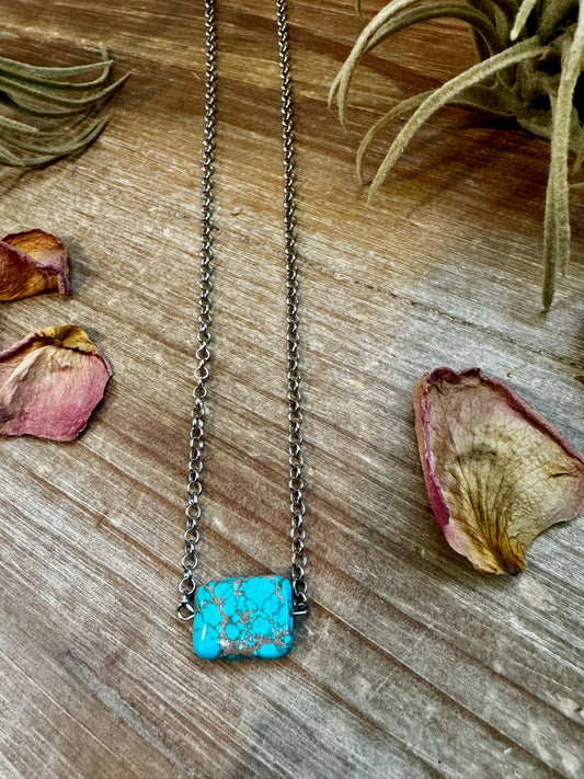 Turquoise stone necklace on wooden surface