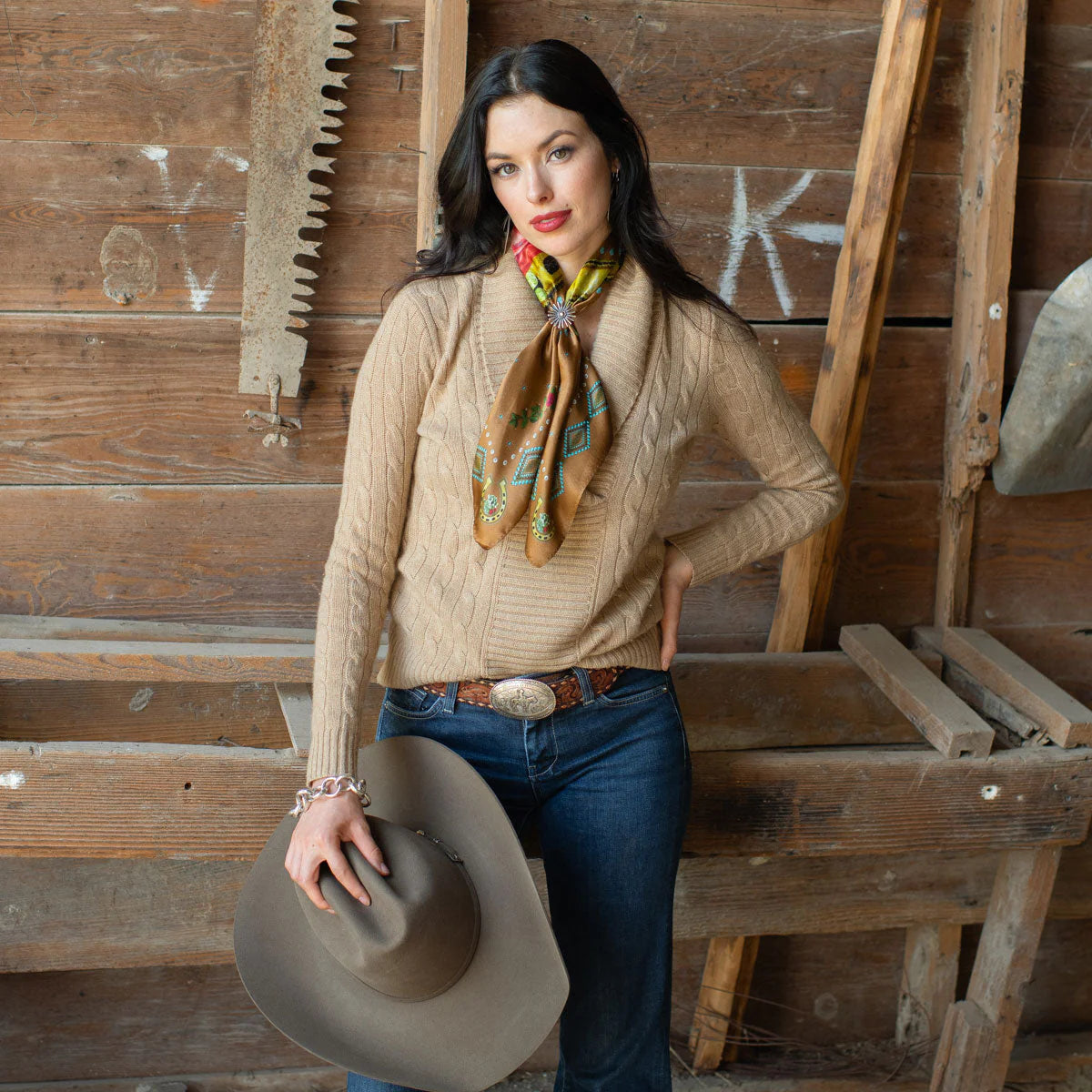 Woman in vintage western wear holding hat.