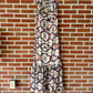 Sleeveless patterned maxi dress hanging on brick wall.