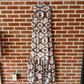 Sleeveless patterned dress hanging on a brick wall.