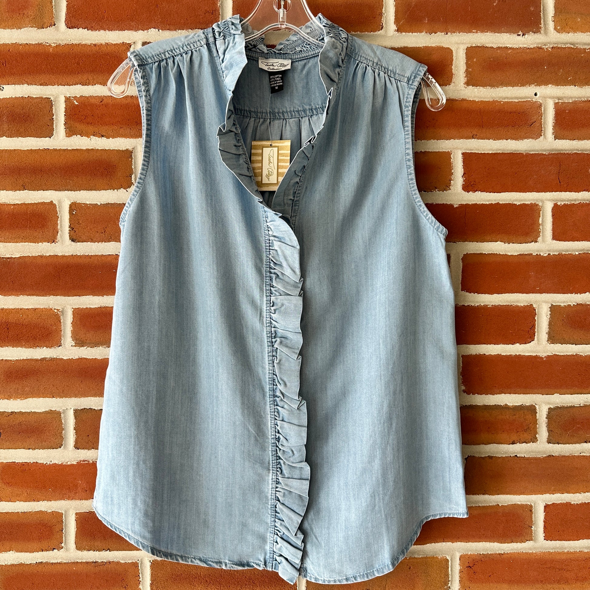 Blue denim sleeveless top with ruffle detail.
