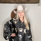 Woman in cowboy hat and horse print shirt.
