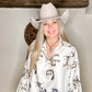 Woman in cowboy hat and horse-print shirt smiles at the camera.