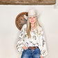 Woman in cowboy hat and shirt, smiling.