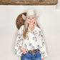 Woman in cowboy hat and patterned shirt.