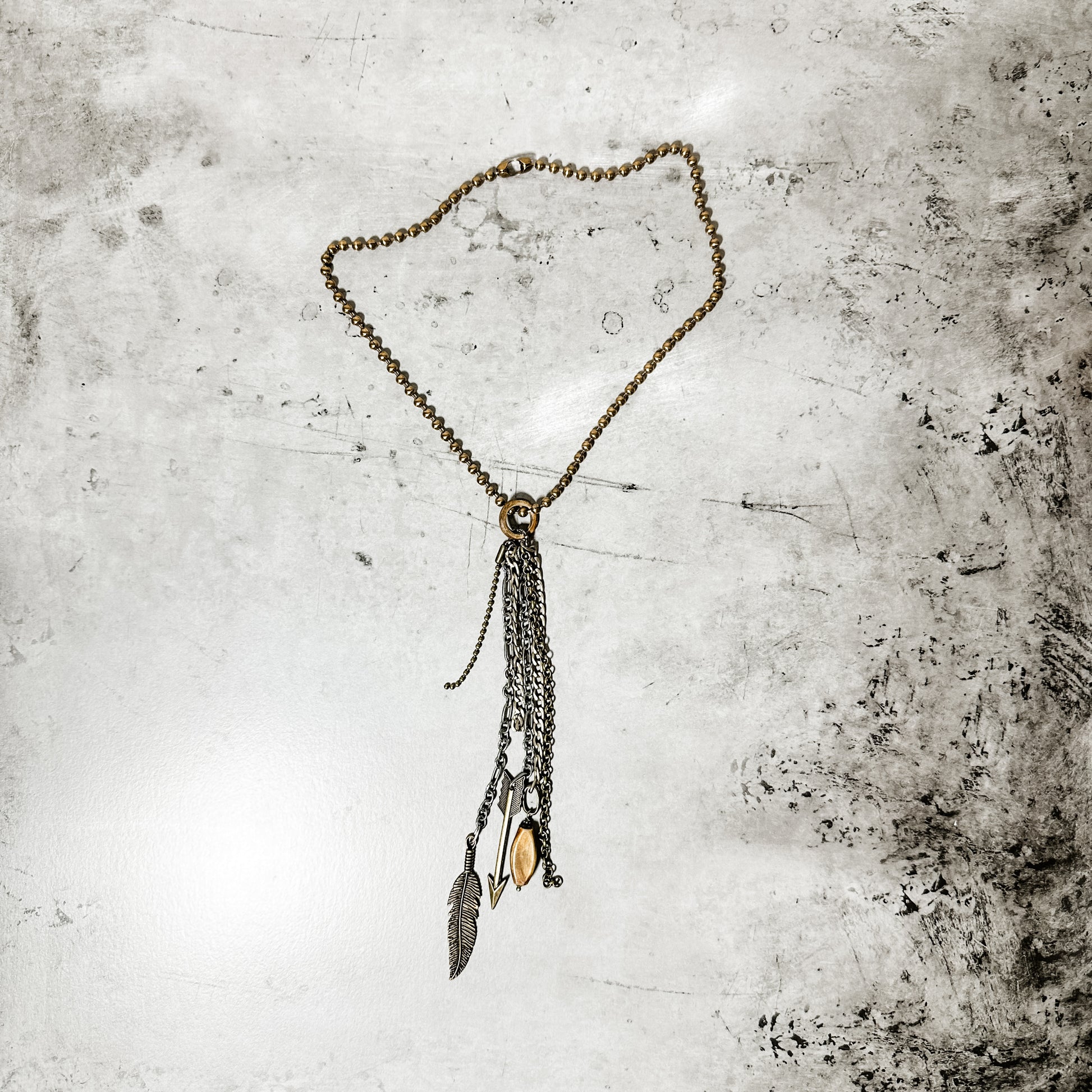 Necklace with dangling chains and feather.