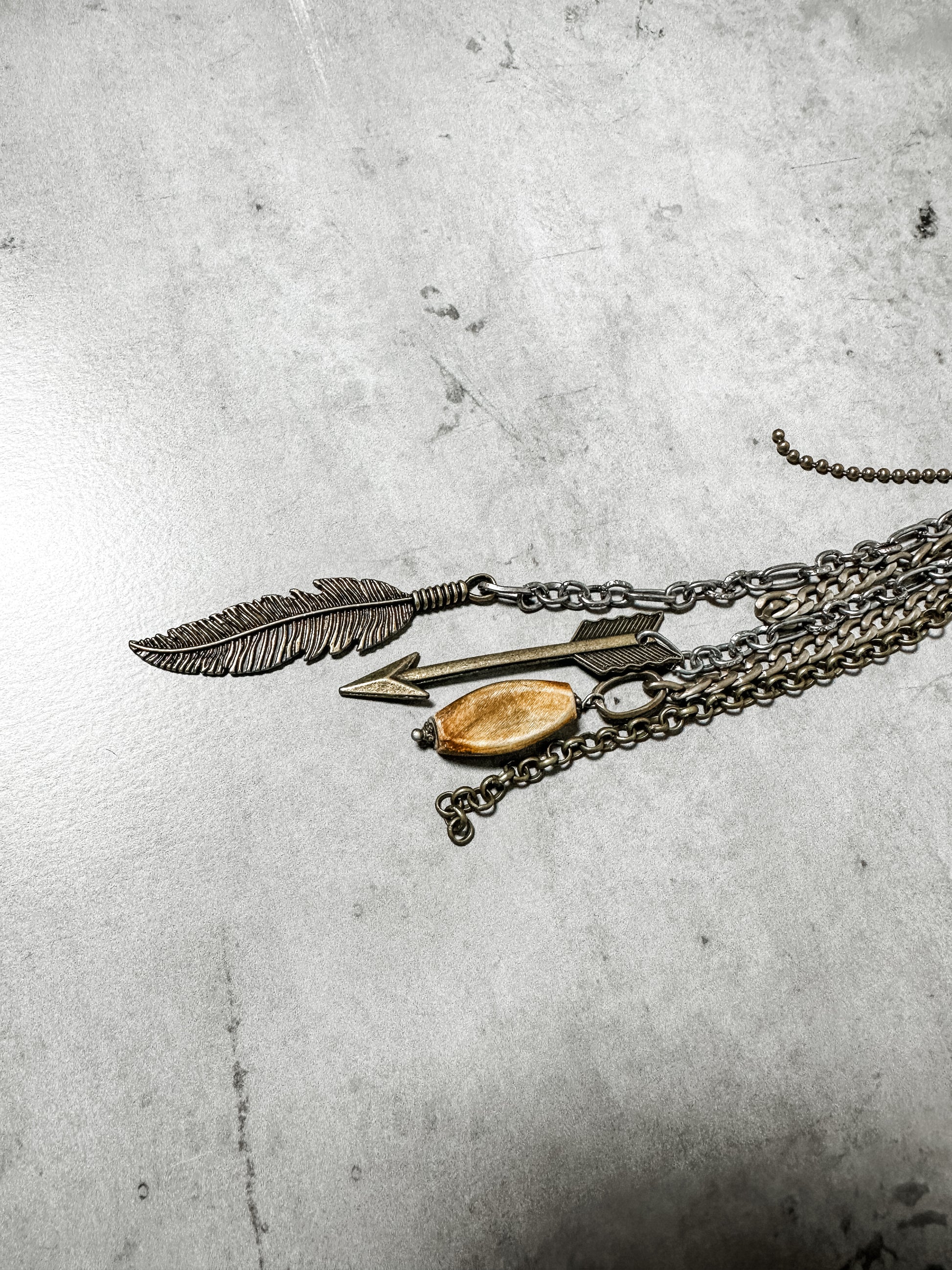 Necklace with feather, arrow, and bead pendants.