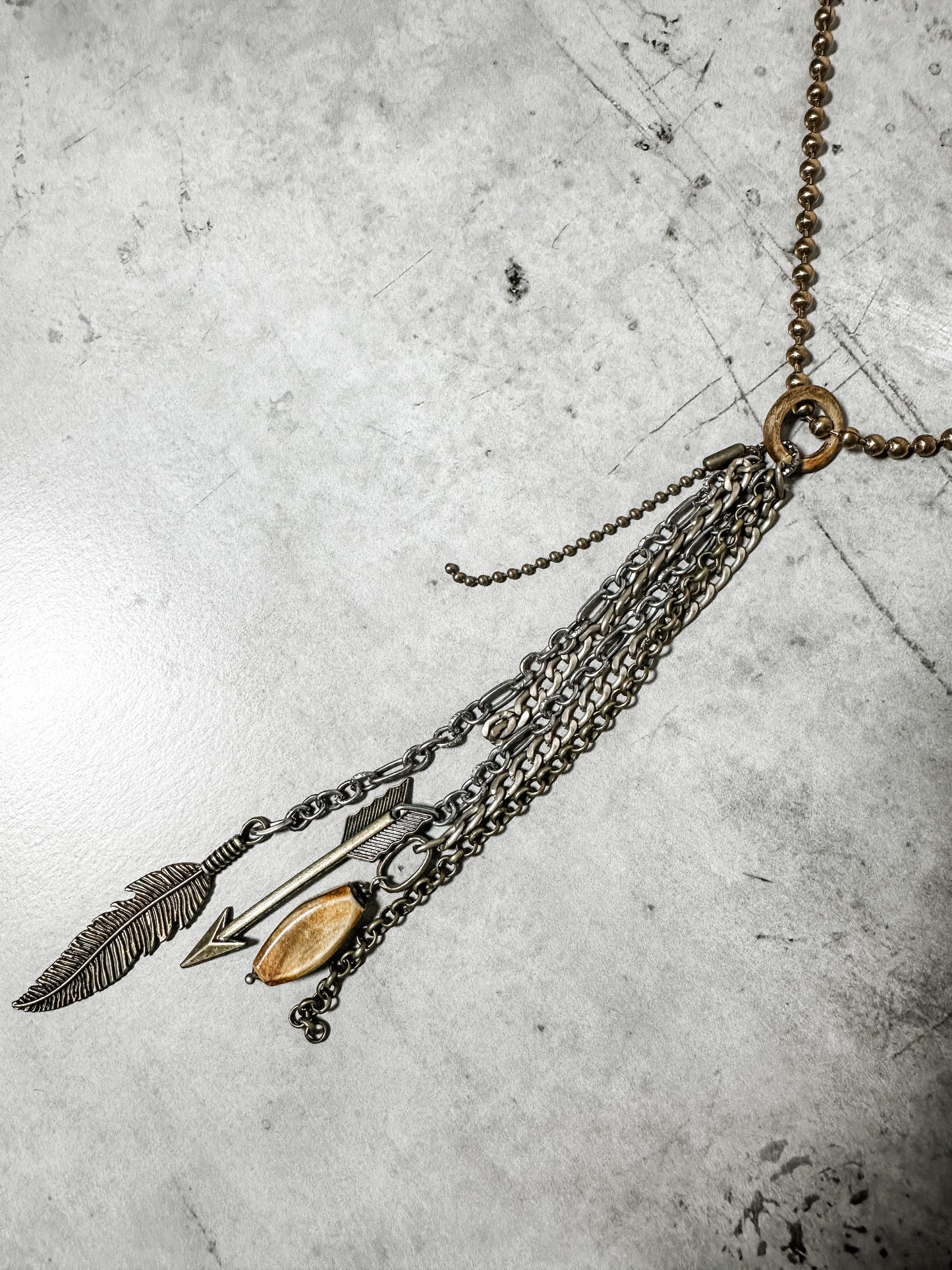 Necklace with charms, including a feather and arrow.