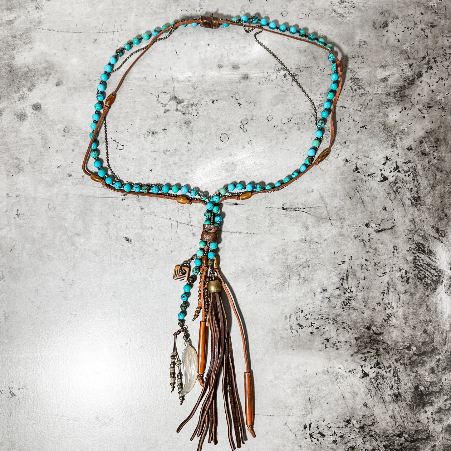 Necklace with turquoise beads and leather tassels.