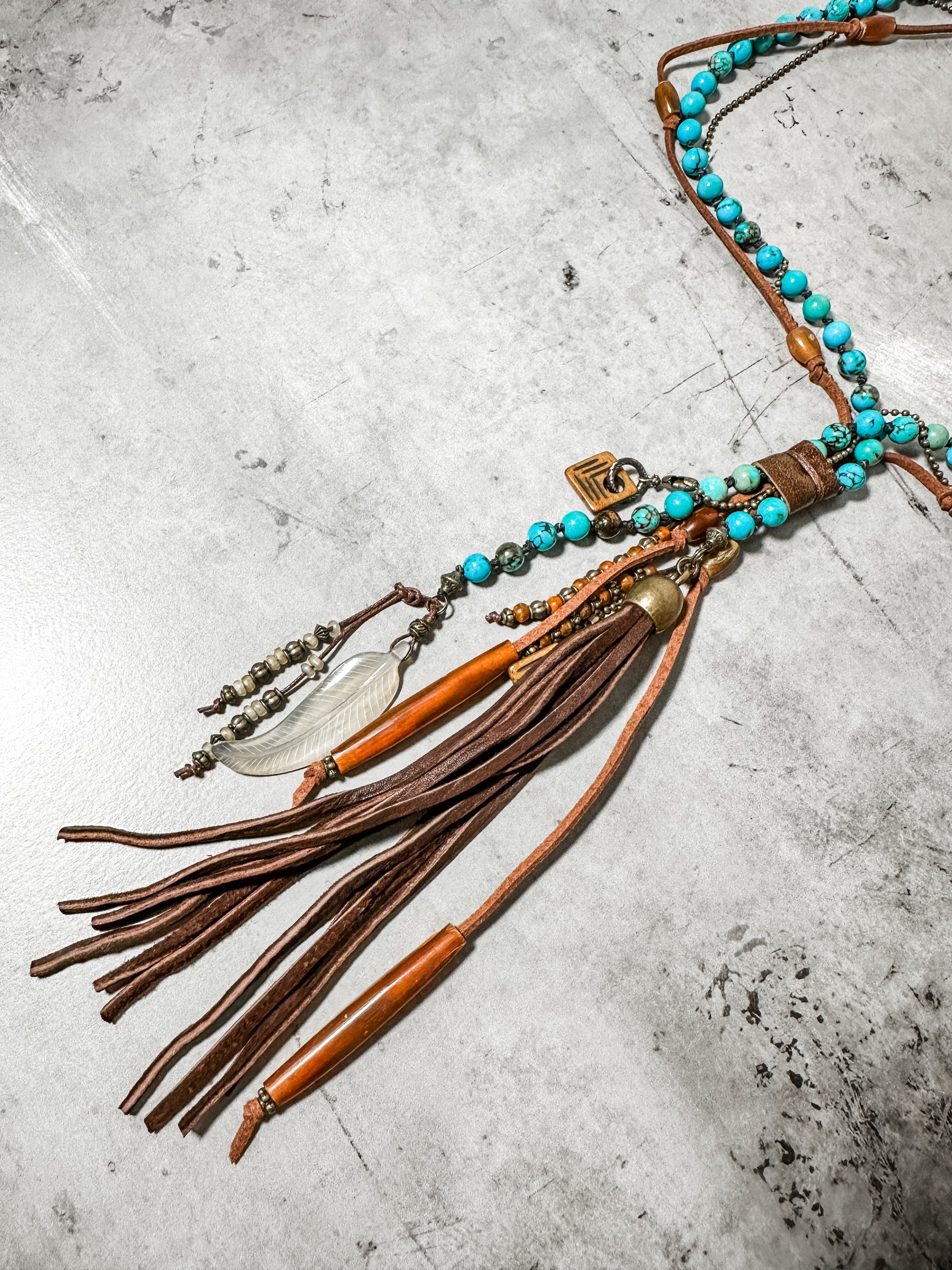 Necklace with turquoise beads and leather tassels.