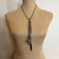 Necklace with chains, stone, and feather on a mannequin.