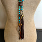 Turquoise beaded necklace with leather tassel on a mannequin.