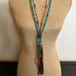 Turquoise bead necklace with leather tassel on a mannequin.