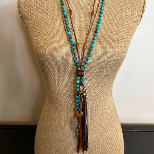 Turquoise bead necklace with leather tassel on a mannequin.