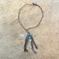 Brown necklace with charms on a textured surface.