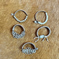 Five silver bracelets on a brown surface.