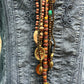 Necklace with beads and charms on denim jacket.