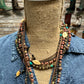 Mannequin wearing layered necklaces and denim shirt.