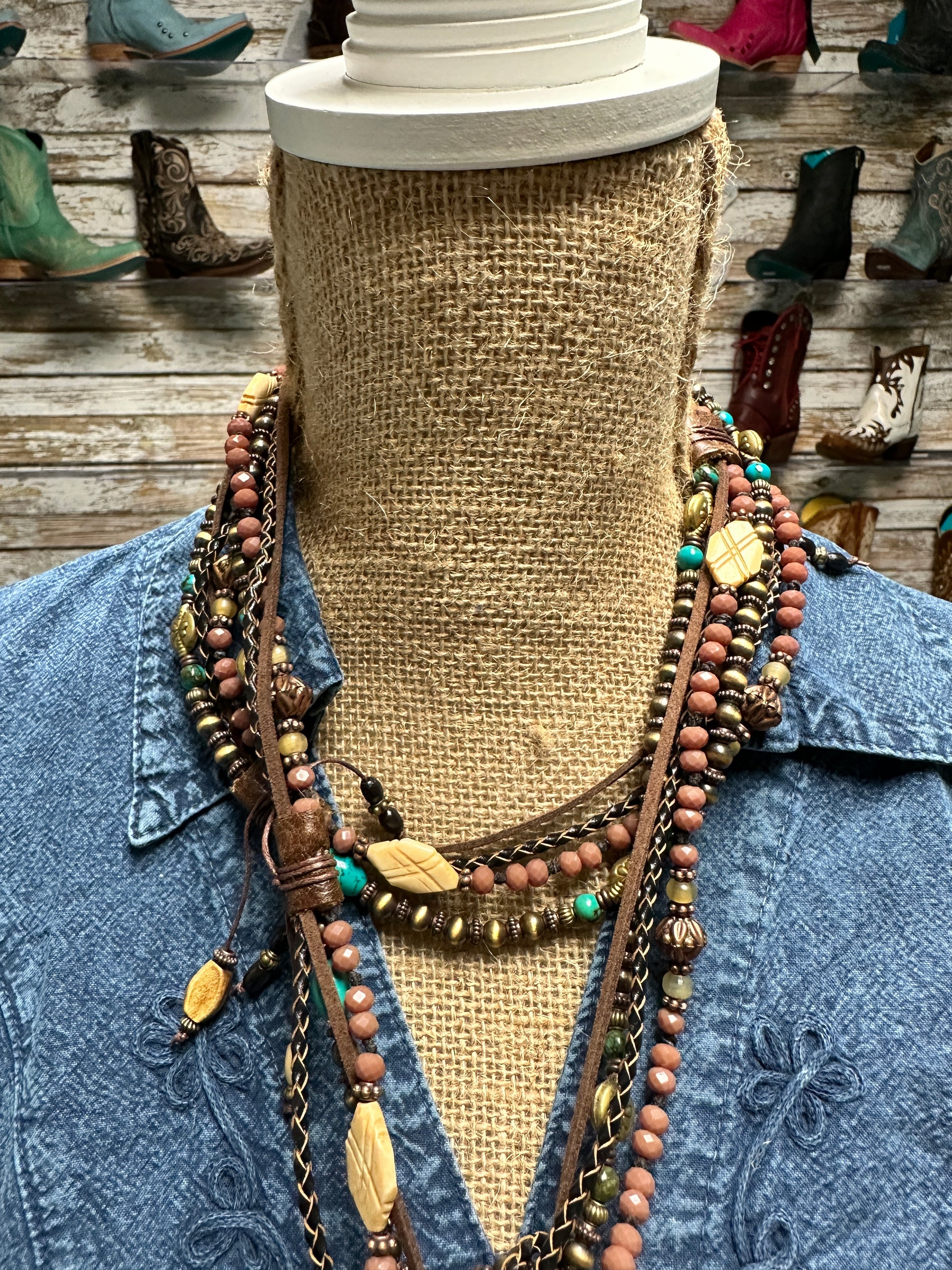 Mannequin wearing layered necklaces and denim shirt.