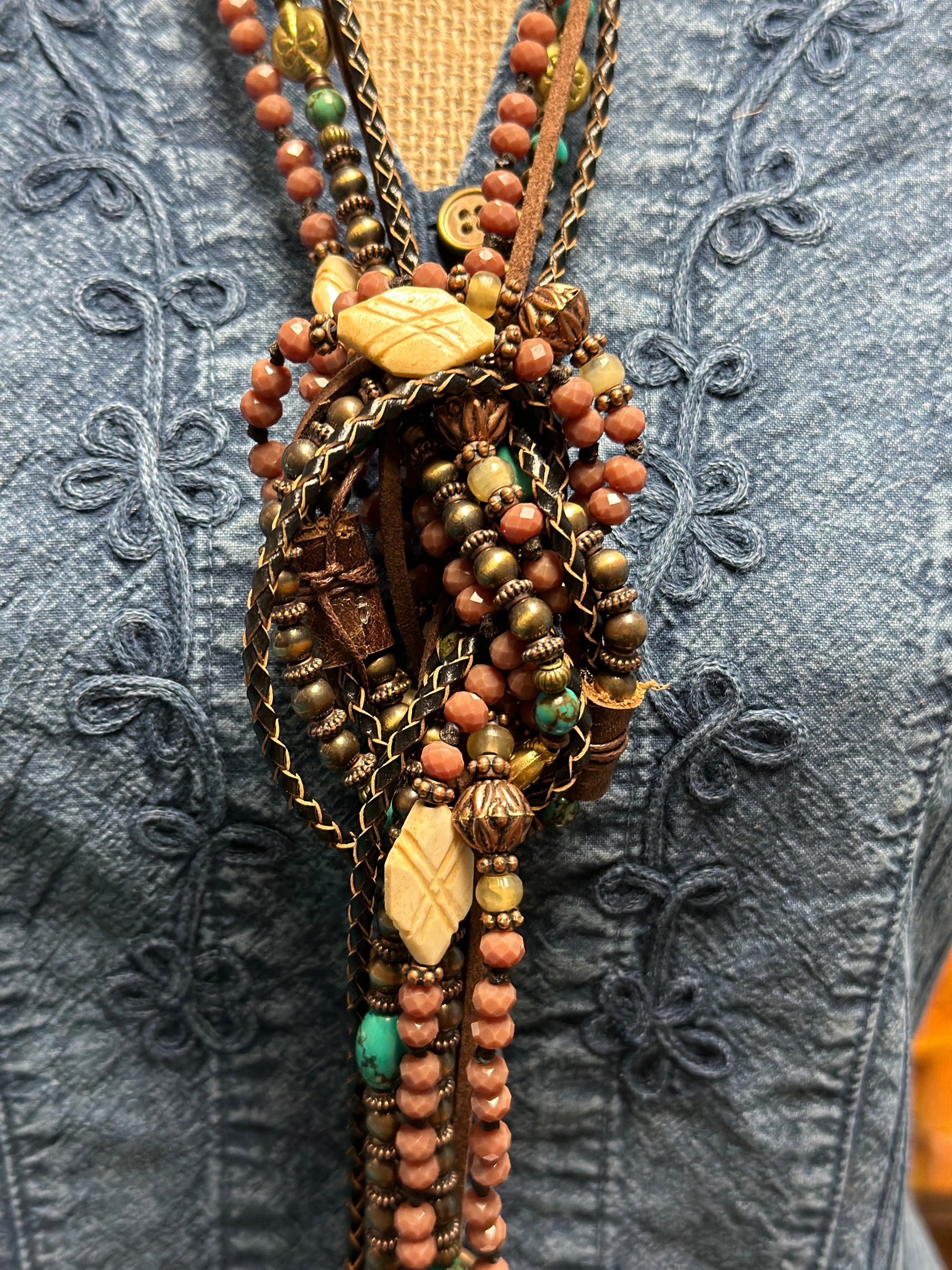 Close-up of a beaded necklace on a denim shirt.