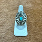 Silver ring with turquoise center on a white stand.