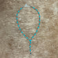 Necklace with turquoise beads on a brown background.