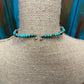 Turquoise beaded necklace on a bust.