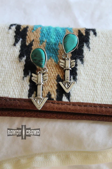 Turquoise arrow earrings on patterned fabric