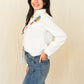 Woman in Whiskey Apparel white embroidered shirt and jeans.