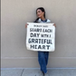 Woman holding Start each day with a grateful heart sign, April 18 screenshot.