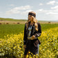 Woman in western attire in a field of wildflowers.