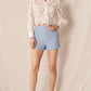 Woman in lace shirt and blue shorts.