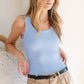 Woman wearing a blue tank top and tan pants.