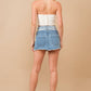 Woman in hat, crop top, denim skirt, and boots.
