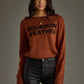 Woman wearing a brown sweater with Bourbon Weather and black pants.