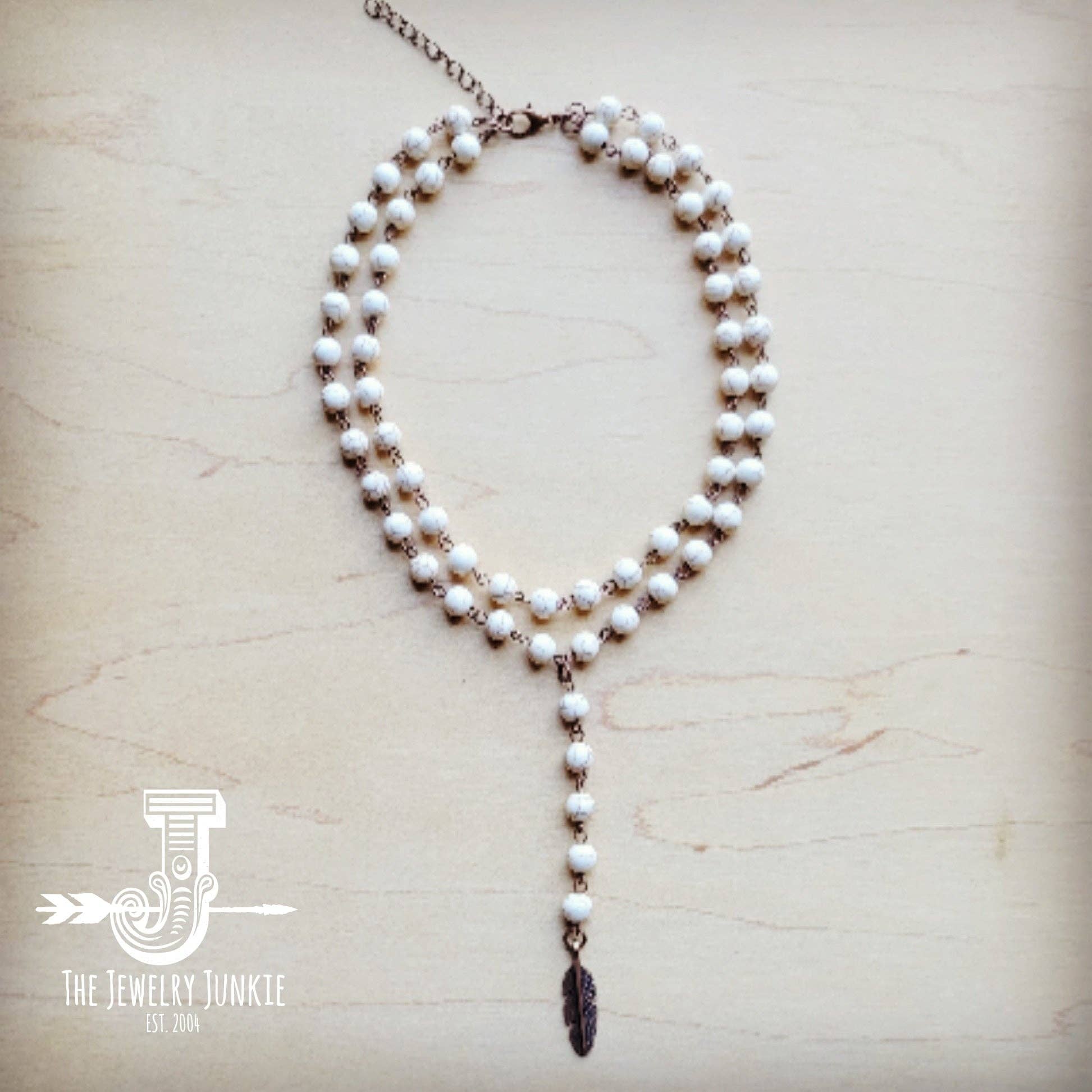 White beaded necklace with feather pendant.