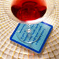 Red drink in glass on decorative plate, with coaster text
