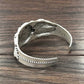 Silver cuff bracelet on wood.