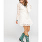Woman in white lace dress and turquoise boots.