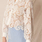 Woman in white lace shirt and blue shorts.